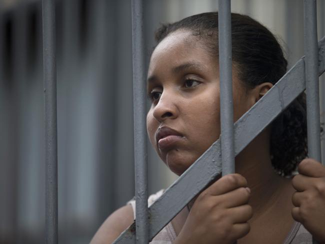 A woman stands behind a gate at the site.