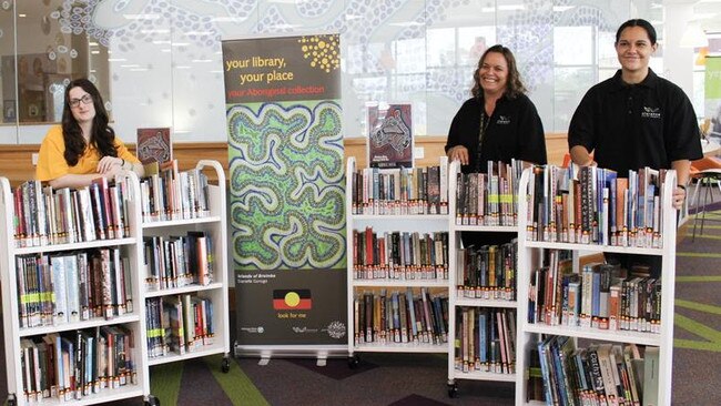 Library team members, (l-r) Tahlia Scherger, Kahlua Charlton and Cate Duroux with the new Aboriginal Collection signage featuring ‘Islands of Breimba’ and some of the books in the collection.