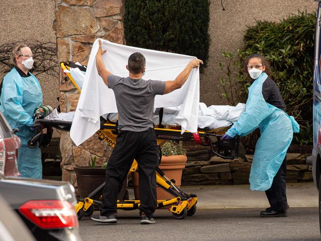 SEATTLE, WA - FEBRUARY 29: Healthcare workers transport a patient on a stretcher into an ambulance at Life Care Center of Kirkland in Kirkland, Washington. Dozens of staff and residents at Life Care Center of Kirkland are reportedly exhibiting coronavirus-like symptoms, with two confirmed cases associated with the nursing facility reported so far.   David Ryder/Getty Images/AFP == FOR NEWSPAPERS, INTERNET, TELCOS & TELEVISION USE ONLY ==