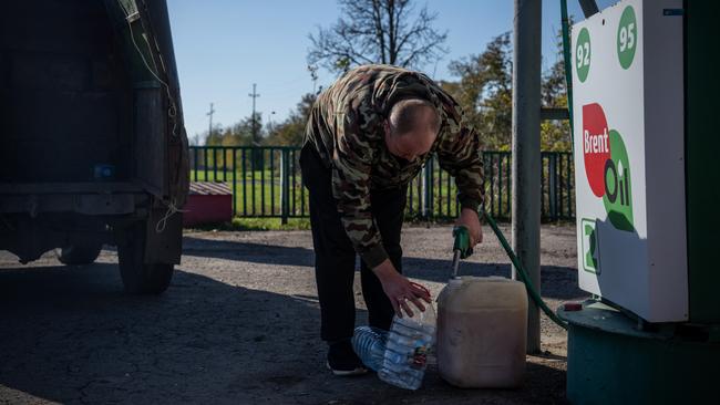 A man fills jerry cans with fuel on October 18 in Kozacha Lopan, Kharkiv oblast, Ukraine after Russian attacks on power stations caused widespread blackouts. Picture: Getty Images