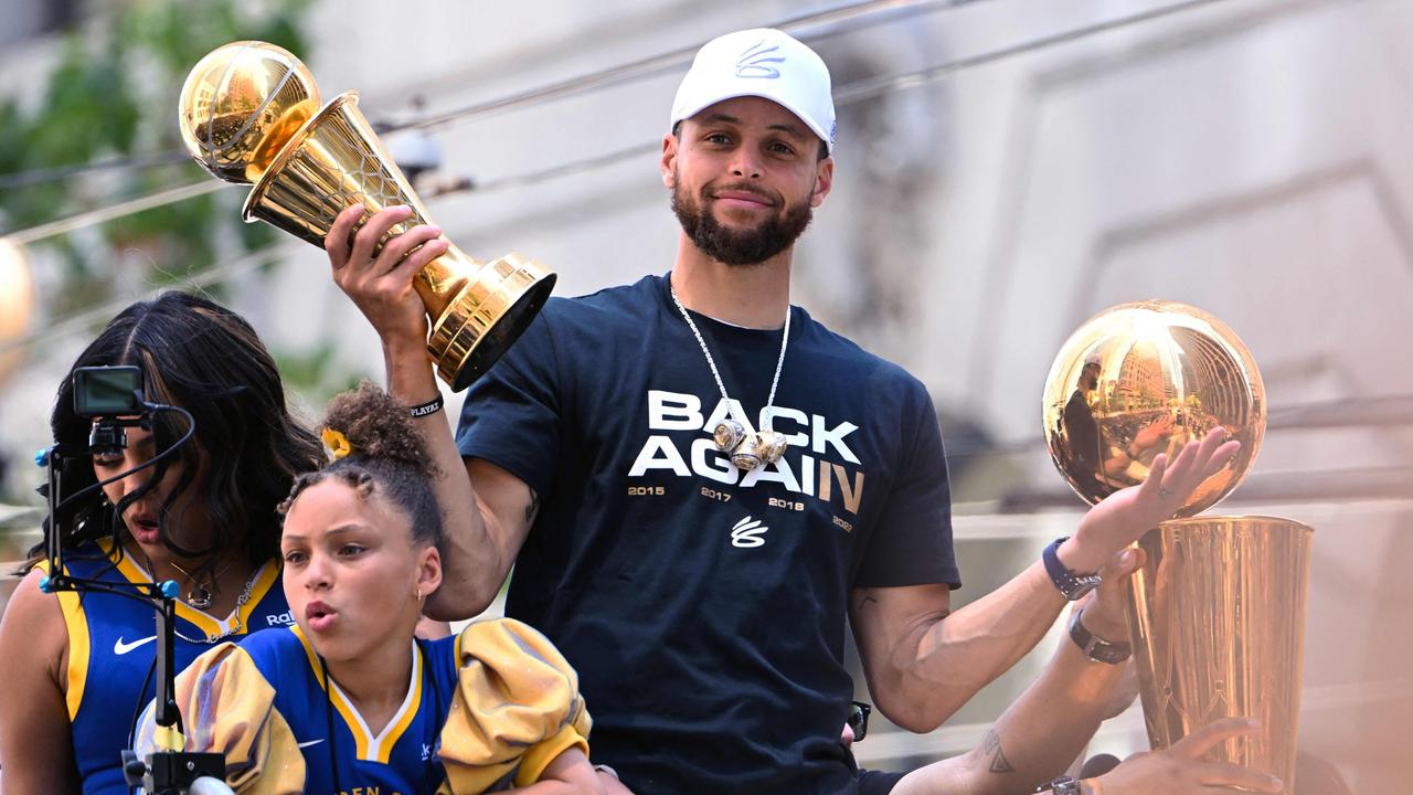 Stephen Curry holds the MVP trophy as he waves from a double decker bus during the Golden State Warriors NBA Championship victory parade. Photo by Patrick T. FALLON / AFP.