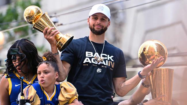 Stephen Curry holds the MVP trophy as he waves from a double decker bus during the Golden State Warriors NBA Championship victory parade. Photo by Patrick T. FALLON / AFP.