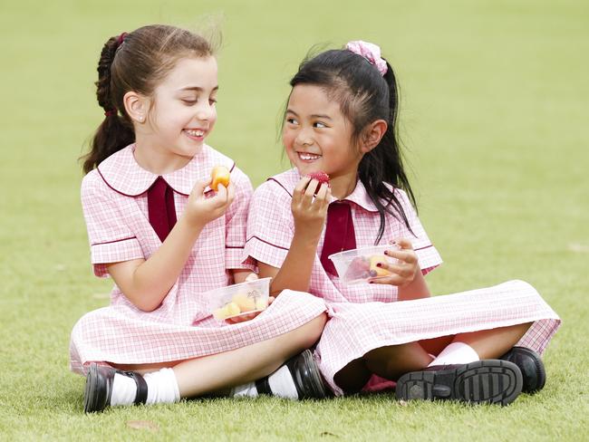 Gabriella Xiberras, 7, and Alexis Montano, 6, eating healthy food from their school canteen at Mary Immaculate Primary School, Quakers Hill. Picture: Justin Lloyd