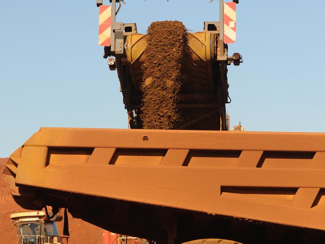 An earth mover receives iron ore from a surface miner in the mine pit at Fortescue Metals Group Ltd.'s Cloudbreak operation in the Pilbara region of Western Australia, on Monday, July 25, 2011. Fortescue Metals Group, Australia's third-biggest producer of iron ore, will release their full-year earnings on August 19. Photographer: Carla Gottgens/Bloomberg