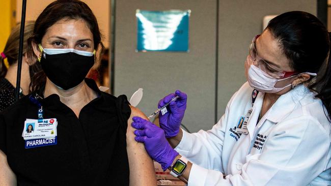 Diana Carolina, a medic at Memorial Healthcare System, receives a Pfizer-BioNtech Covid-19 vaccine from Monica Puga at Memorial Healthcare System, in Miramar, Florida on December 14, 2020. - The United States kicked off a mass vaccination drive Monday hoping to turn the tide on the world's biggest coronavirus outbreak, as the country's death toll neared a staggering 300,000. (Photo by CHANDAN KHANNA / AFP)