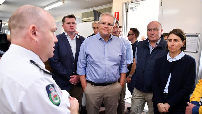 Scott Morrison and NSW Premier Gladys Berejiklian are briefed during a visit to the Wollondilly Emergency Control Centre in Sydney on Sunday.