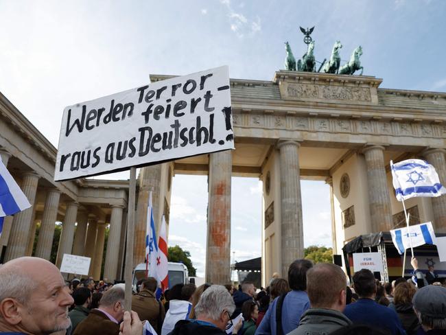 People wave Israeli flags and a banner reading "Who celebrates terror – leave Germany" during a demonstration in support of Israel called by Jewish organisations in front of landmark Brandenburg Gate in Berlin. Picture: AFP