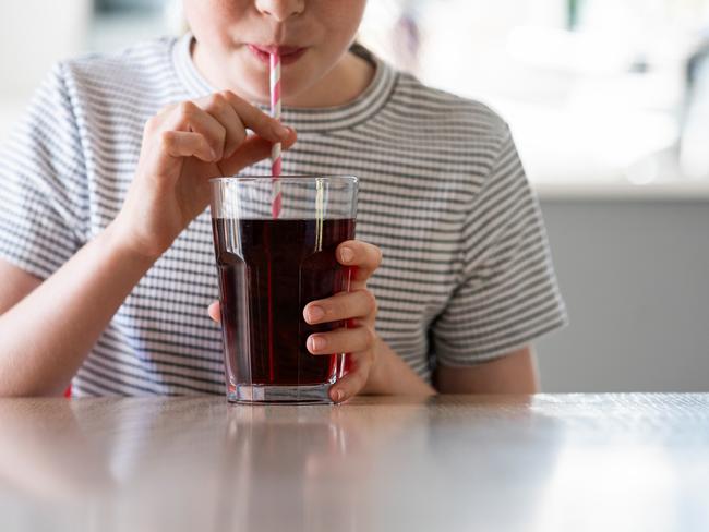 IStock generic of kids drinking -  Close Up Of Girl Drinking Sugary Fizzy Soda From Glass With Straw