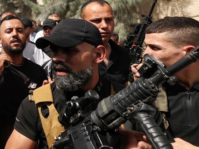 EDITORS NOTE: Graphic content / TOPSHOT - Mourners and armed militants carry the body of Islam Khamayseh, a local commander of Al-Quds Brigade, the armed wing of militant group Palestinian Islamic Jihad, killed in an overnight Israeli strike on the occupied West Bank Jenin refugee camp, during his funeral on May 18, 2024. (Photo by Zain JAAFAR / AFP)