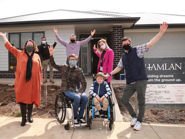 Single dad Aaron McArthur and his son, Abel, have moved into a specially built home to suit his disability. They are pictured with disability advocates who helped make it happen. Picture: Alison Wynd