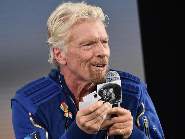 Sir Richard Branson holds up photos that he brought with him into space. The trip proceeded without drama, and touchdown occurred about an hour after take-off. Picture: AFP