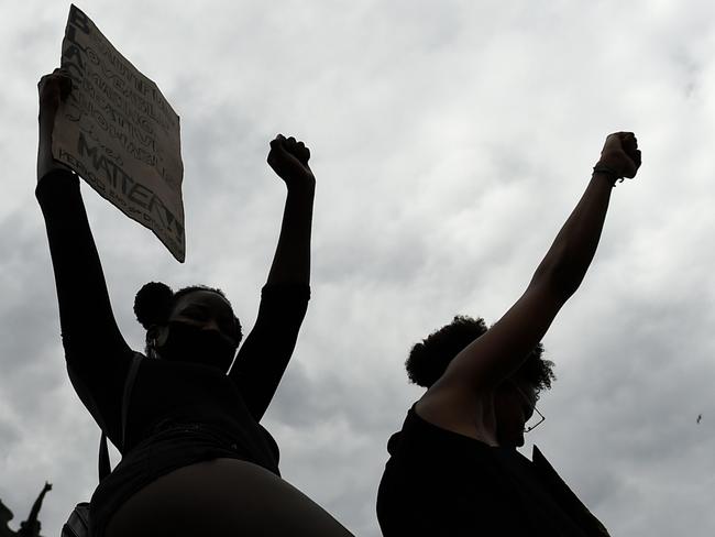 Protesters raise their fists next to the statue of Christopher Columbus during a demonstration  in Barcelona,  on June 14, 2020, as part of the worldwide protests against racism and police brutality. - Statues of Christopher Columbus from Boston to Miami have been beheaded and vandalized as calls to remove sculptures commemorating colonizers and slavers sweep America on the back of anti-racism protests sparked by the death of George Floyd. (Photo by Josep LAGO / AFP)