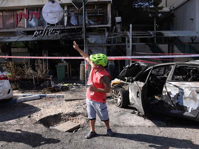 An Israeli man gestures towards damaged vehicles and buildings after a rocket attack from southern Lebanon on the Israeli city of Kiryat Shmona in northern Israel. Picture: AFP