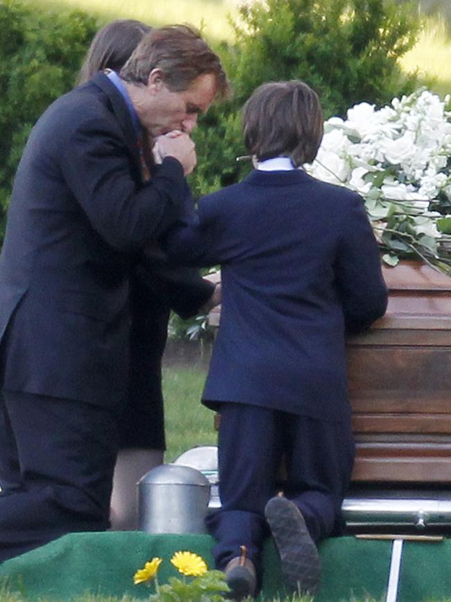 Robert F. Kennedy Jr., left, kneels with his children at the casket of Mary Richardson Kennedy, in St. Francis Xavier Cemetery in 2012. (AP Photo/Michael Dwyer)