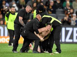 CAUGHT: A streaker is rounded up by security after disrupting the NRL Round 17 clash between the Tigers and Eels. Picture: JOEL CARRETT