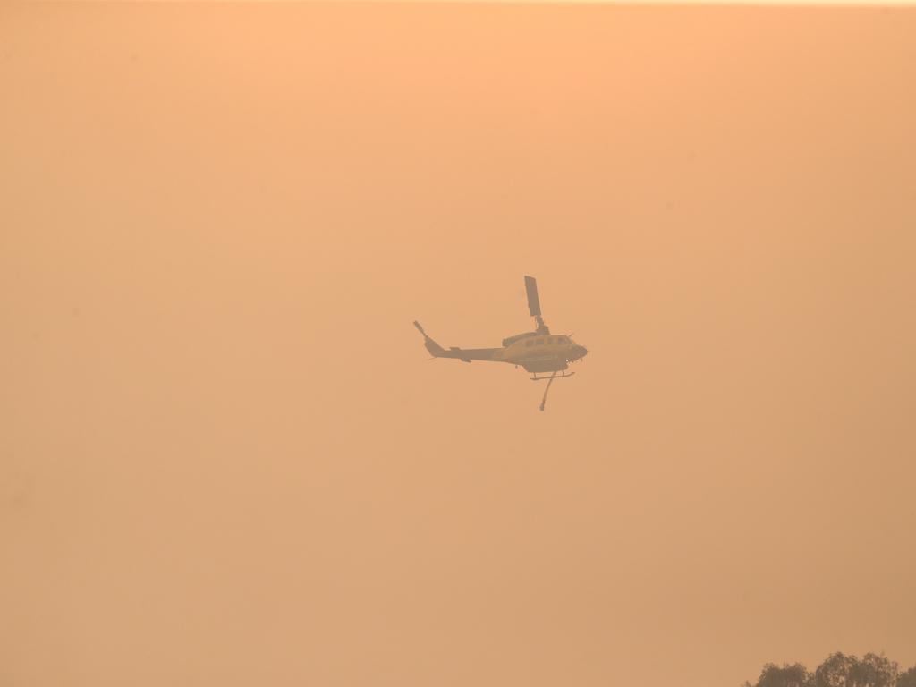 A helicopter tackling the fire heading towards Mt Larcom. Picture: Mark Cranitch.