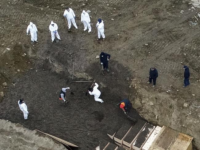 Workers wearing personal protective equipment bury bodies in a trench on Hart Island in New York’s Bronx neighbourhood. Picture: AP