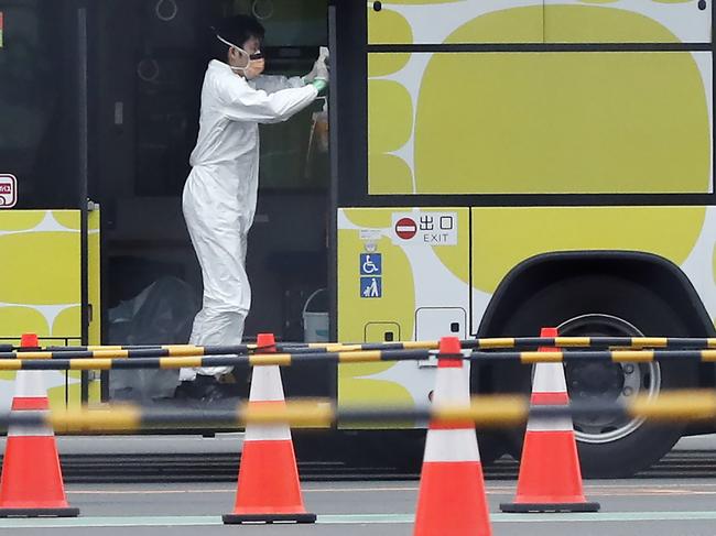 A worker cleans a bus used for carrying the passengers from the quarantined Diamond Princess cruise ship leaves a port in Yokohama, near Tokyo, Thursday, Feb. 20, 2020. The cruise ship started letting passengers who tested negative for the virus leave the ship Wednesday. Test results are still pending for some people on board. (AP Photo/Eugene Hoshiko)