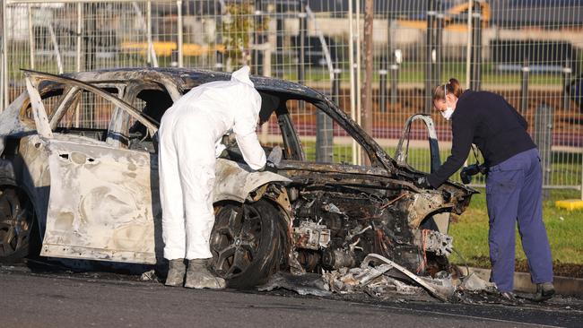 Investigators comb a burnt-out car for evidence on St Georges Boulevard. Picture: Brendan Beckett