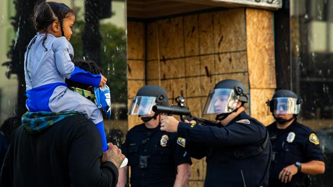 A man stands with his child in front of police during demonstrations in downtown Long Beach, California. Picture: Richard Grant