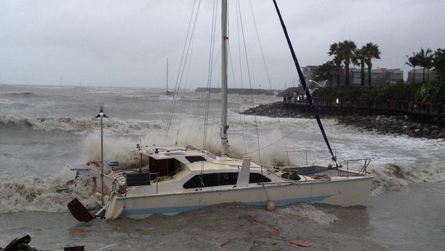 A catamaran is washed up during heavy seas in Cannonvale near Airlie Beach in the Whitsundays in Queensland. Picture: AAP