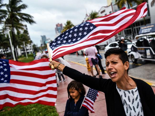 A protestor shouts slogans and waves a US flag as she participates in a "Freedom Rally" protest in support of opening Florida in South Beach in Miami, on May 10, 2020. (Photo by CHANDAN KHANNA / AFP)