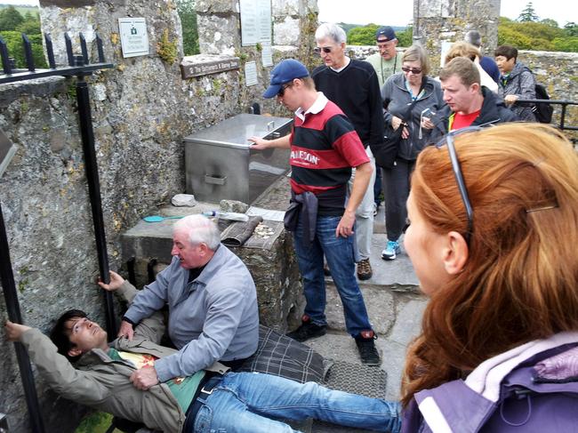 A tourist prepares to lean backwards to kiss the Blarney stone. Picture: Supplied