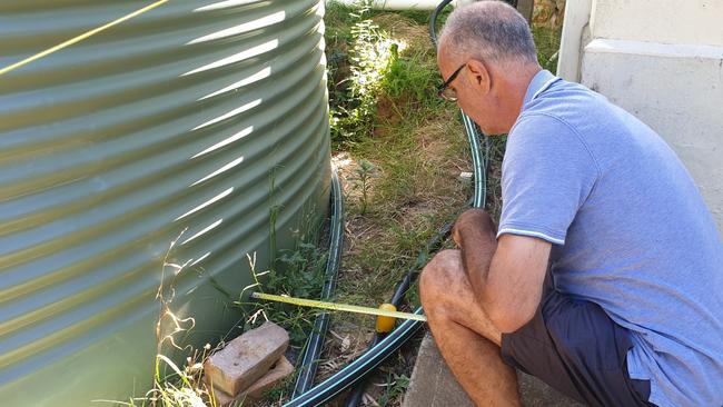 Branko Soda measures the rainwater tank put next to his home. Picture: Colin James