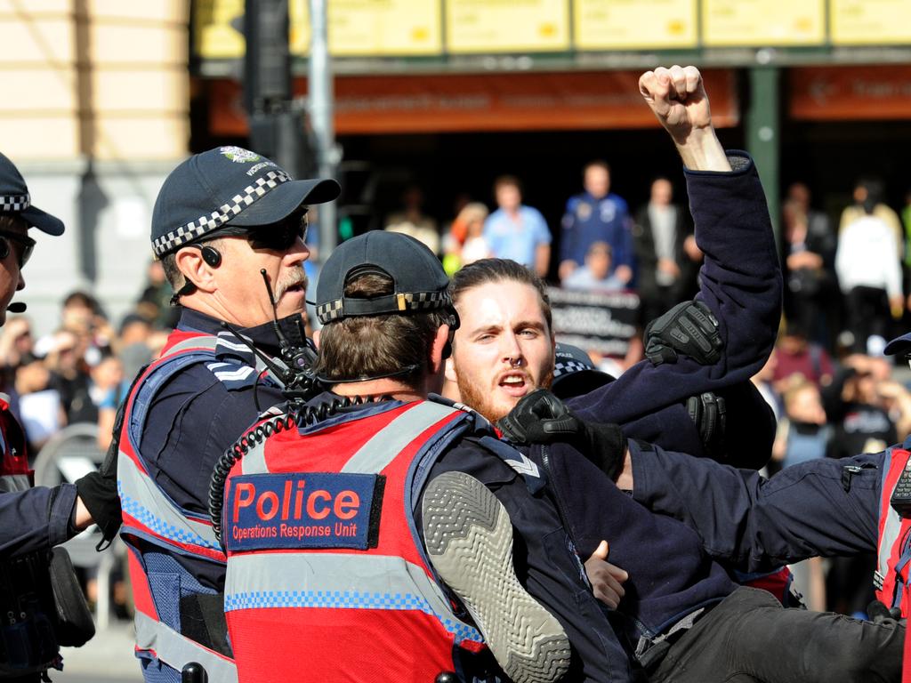 Police move in to remove vegan protesters from Flinders and Swanston streets. Picture: Andrew Henshaw