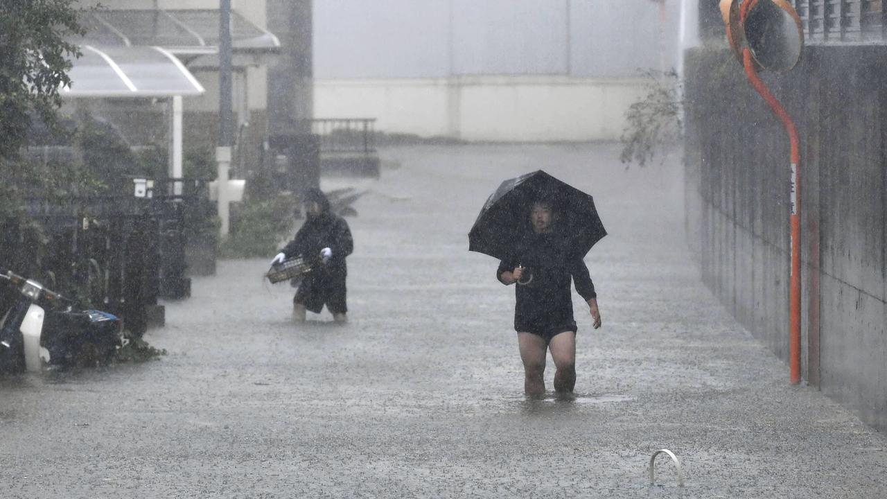 People walk through a flooded street affected by Typhoon Hagibis, in Shizuoka, central Japan. Picture: Kyodo News via AP