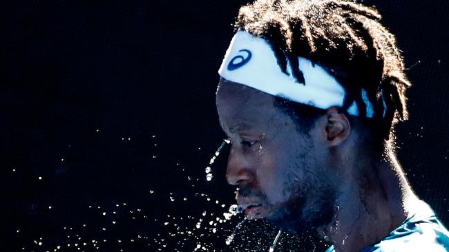 Gael Monfils spits out water as he attempts to cool down between games.
