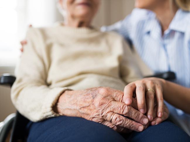 Unrecognizable senior woman in wheelchair with a health visitor at home at Christmas time.