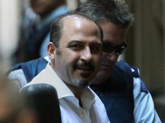 Tony Mokbel flashes a grin as he’s led into the Supreme Court in 2011.