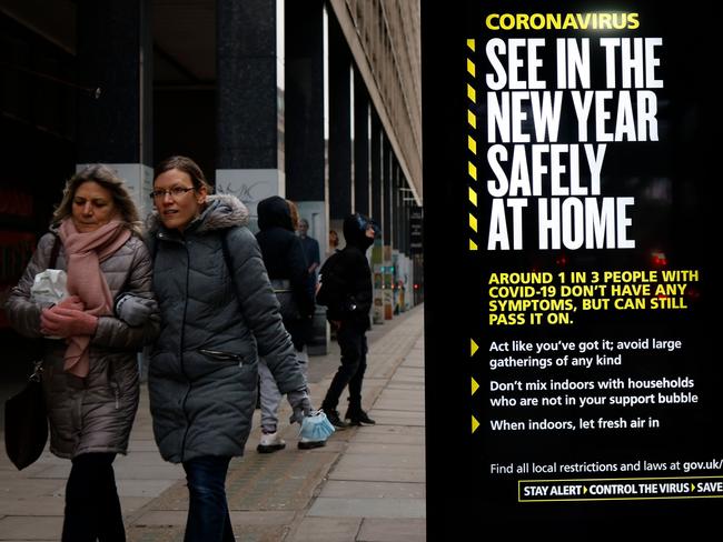 Pedestrians walk past a London bus stop with a government message about Tier 4 restrictions. Picture: AFP