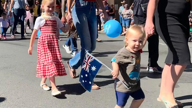 A young Aussie waving the Australian flag at the Gympie 2024 Anzac Day parade.