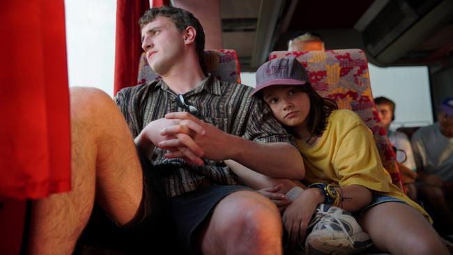 Sophie (Frankie Corio) rests her head against Calum’s (Paul Mescal’s) shoulder as they travel by bus in Aftersun