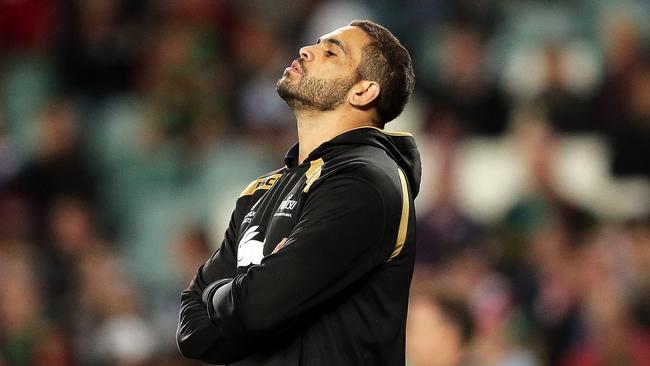 The injured Greg Inglis watches Rabbitohs teammates warm up prior to a game.