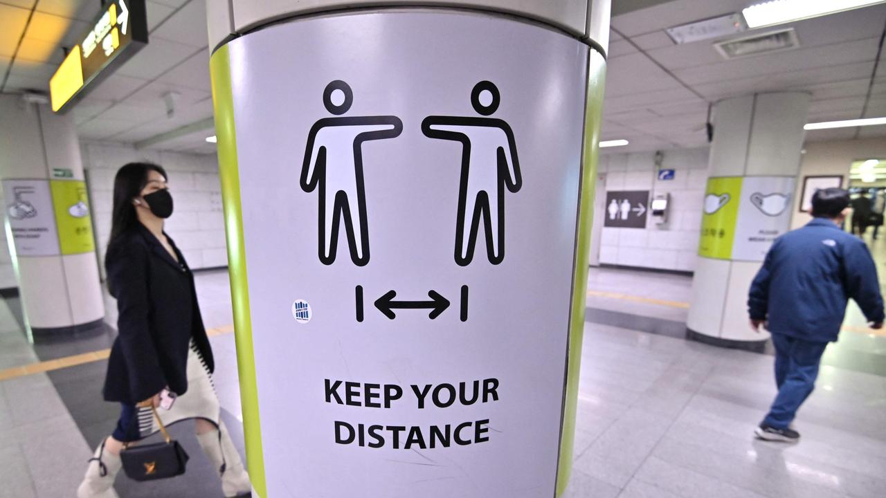 A woman walks past a poster showing precautions against the Covid-19 coronavirus at a subway station in Seoul. Picture: AFP.