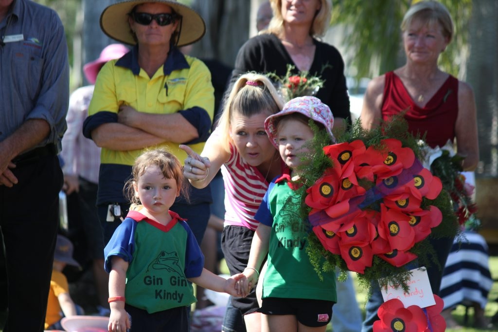 Amelia Schmidt and Zahliah Collins receive instruction from Brodie Collins on where to lay their Gin Gin Kindy wreath. Photo Leah Kidd / NewsMail. Picture: Leah Kidd