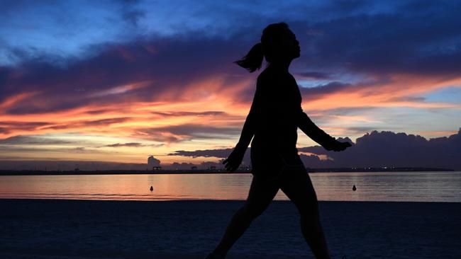 A walker at Brighton-Le-Sands beach at sunrise on Thursday. Picture: Dean Lewins/AAP