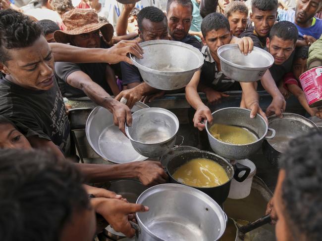 Palestinians struggle to receive cooked food distributed at a community kitchen in Khan Younis, southern Gaza Strip, Wednesday, May 14, 2025. (AP Photo/Abdel Kareem Hana)