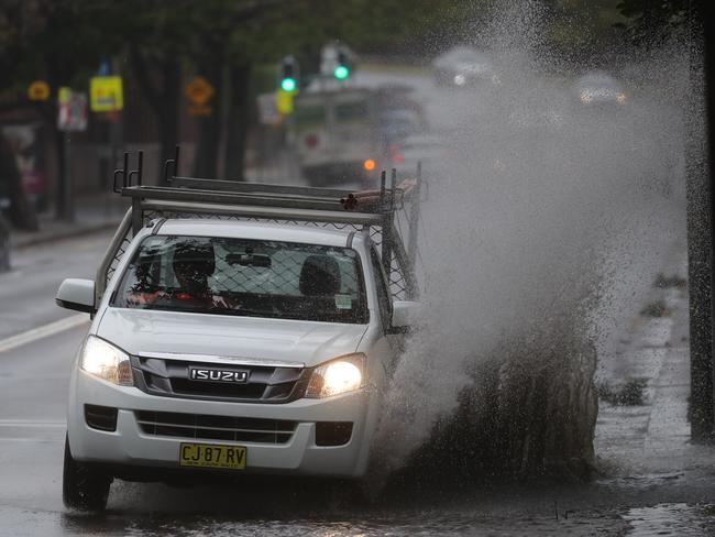 Motorists along Lang Rd, at Moore Park in Sydney drive through flash flooding.