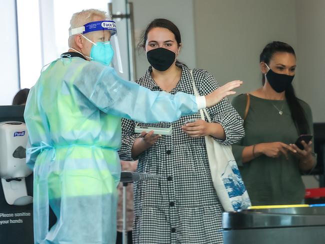 COVID-19 compliance officers check the documents of returning travellers from Brisbane in the Qantas terminal. Picture: Ian Currie