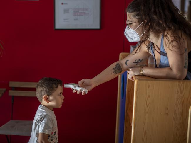 Hugo, 3, has his temperature taken by a teacher as he arrives at Cobi kindergarten in Barcelona, Spain, Friday, June 26, 2020. Spain's cabinet will extend the furlough schemes adopted during the coronavirus lockdown that brought the economy to a standstill until the end of September. (AP Photo/Emilio Morenatti)