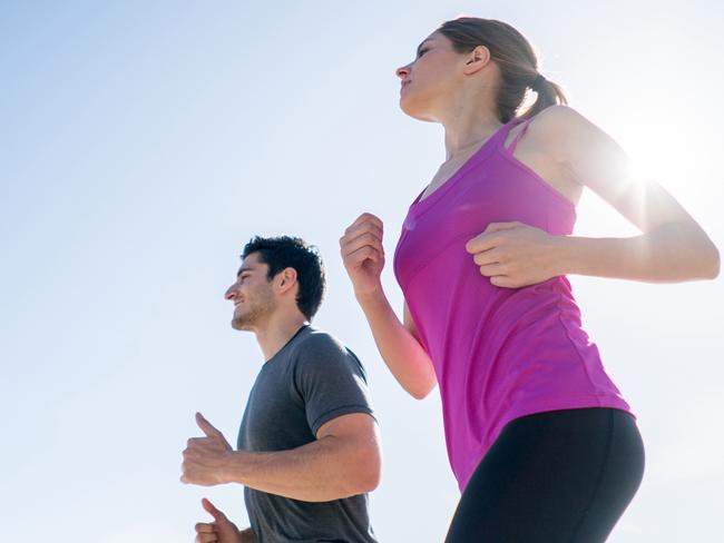 Fit couple of people running at the beach and looking happy exercising