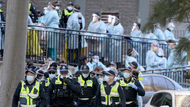 Police and healthcare workers prepare to enter one of the towers at the North Melbourne public housing estate. Picture: NCA NewsWire / Andrew Henshaw