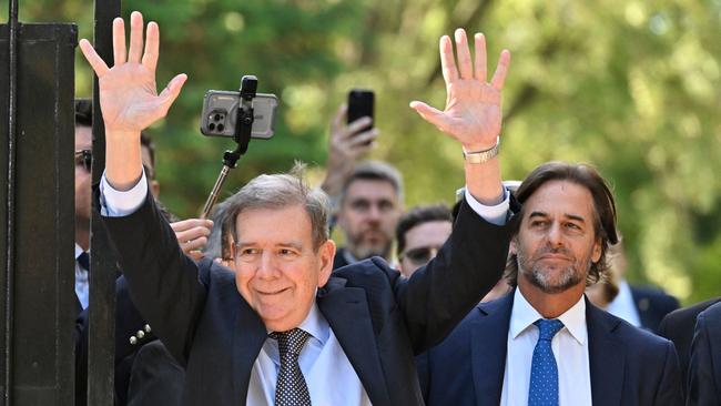 Venezuelan opposition leader Edmundo Gonzalez Urrutia waves to supporters next to Uruguay's President Luis Lacalle Pou.