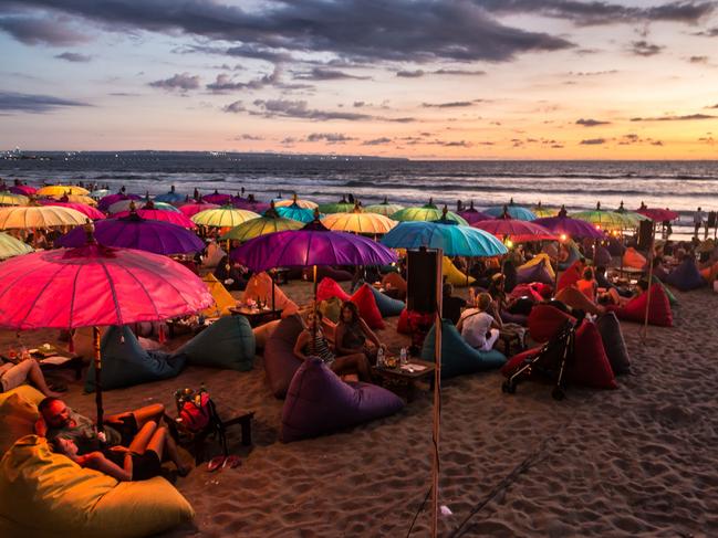 Tourists enjoy the sunset at a beach bar on Kuta beach in Seminyak, Bali.