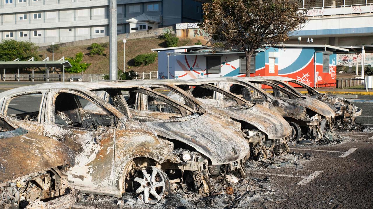 A photo shows burnt-out cars in the parking lot of the old hospital on the outskirts of Noumea on May 16, 2024, amid protests linked to a debate on a constitutional bill aimed at enlarging the electorate for upcoming elections of the overseas French territory of New Caledonia. France deployed troops to New Caledonia's ports and international airport, banned TikTok and imposed a state of emergency on May 16 after three nights of clashes that have left four dead and hundreds wounded. Pro-independence, largely indigenous protests against a French plan to impose new voting rules on its Pacific archipelago have spiralled into the deadliest violence since the 1980s, with a police officer among several killed by gunfire. (Photo by Delphine Mayeur / AFP)