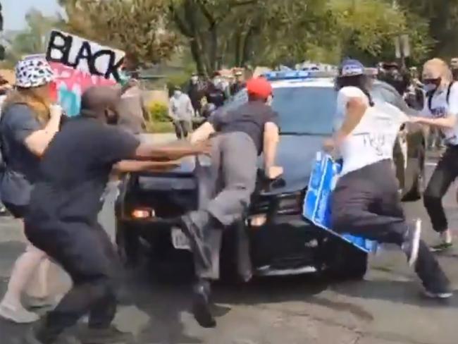 Police car drives through anti-Trump protesters in California.